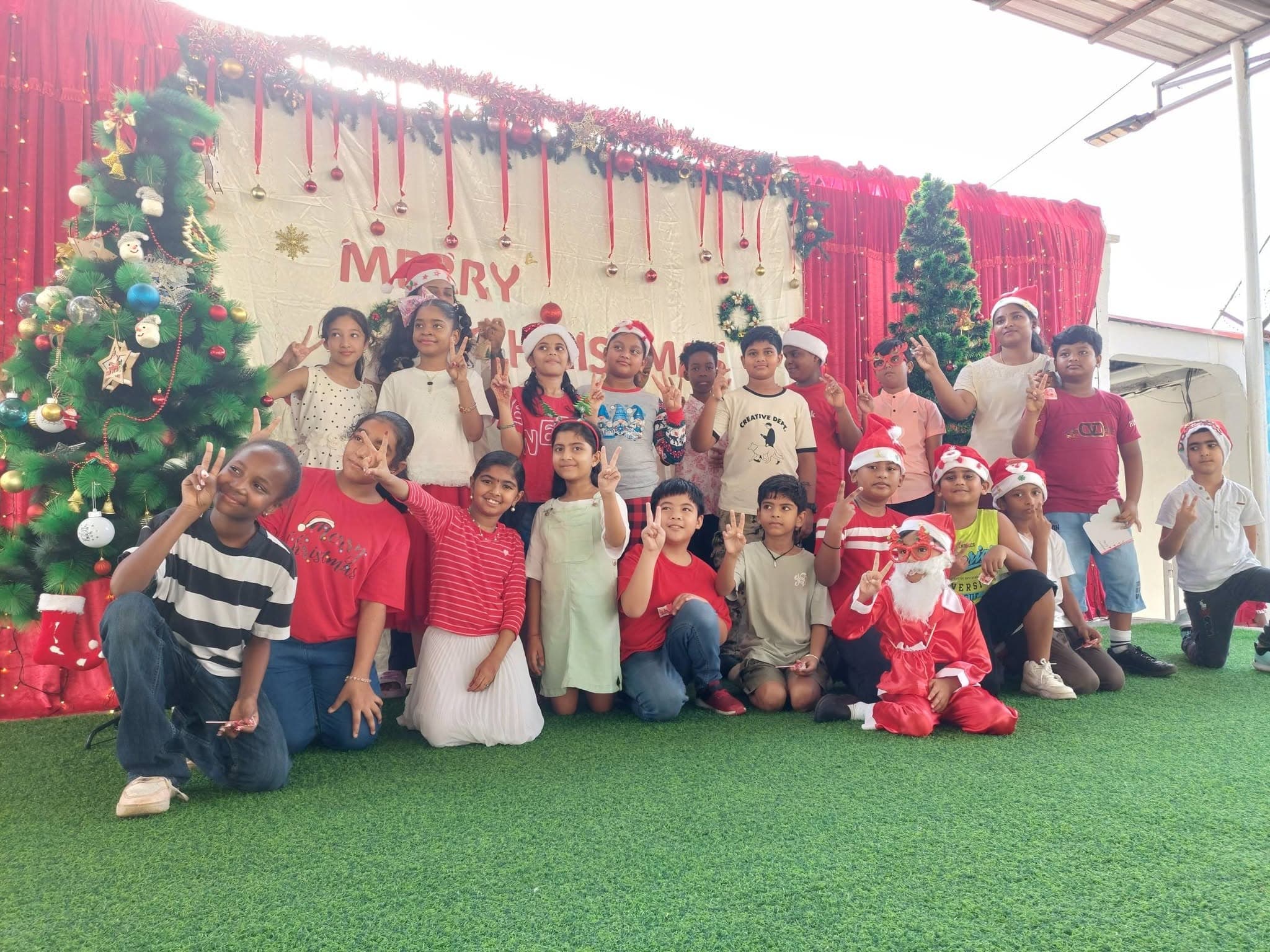 Students posing by the Christmas tree on the decorated stage