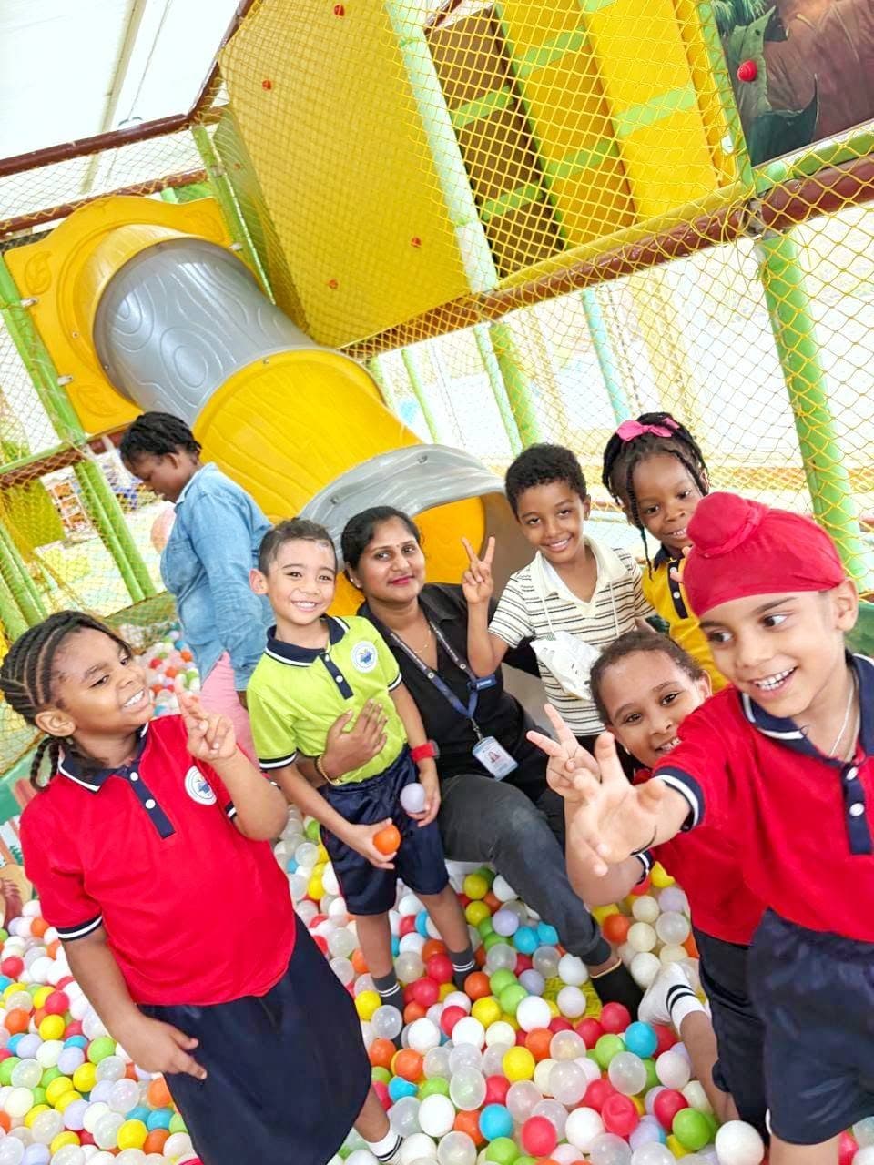 Students and a teacher smiling in the ball pit on outing day